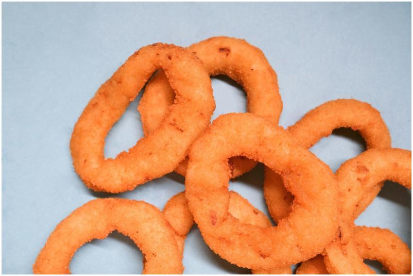 Crispy golden onion rings on a vibrant blue backgr