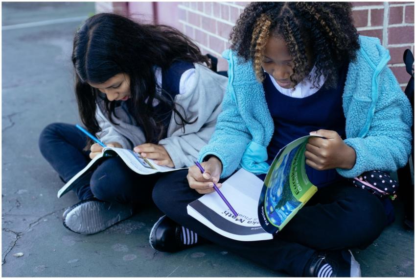 Two young students sitting on the ground, focused