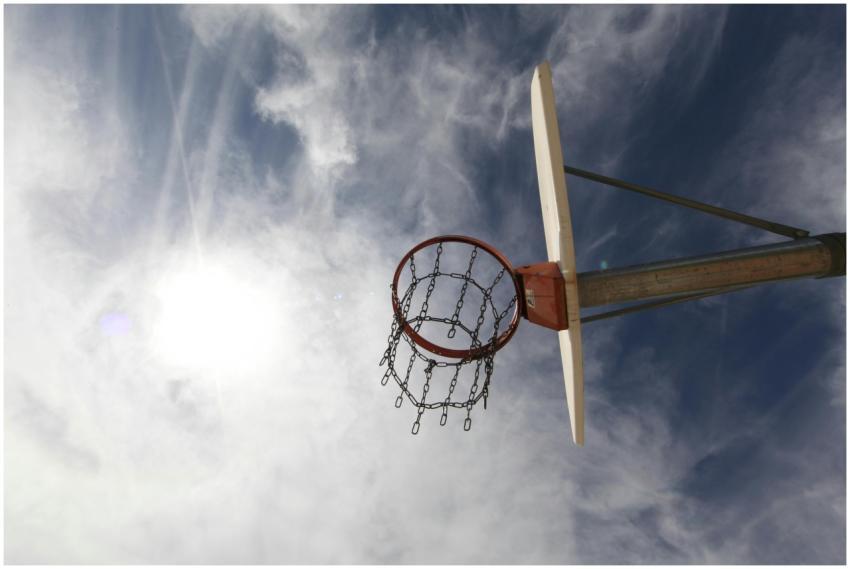 A basketball hoop with a chain net is silhouetted
