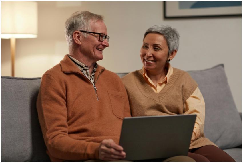 Senior couple smiling and using a laptop together