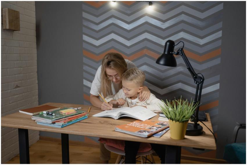 A mother assists her son with homework at a desk,