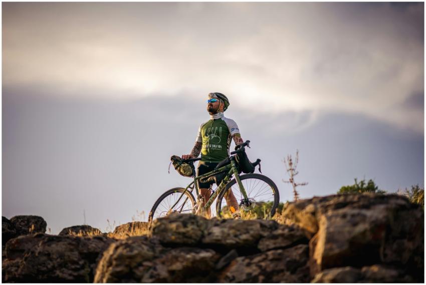An adventurous cyclist poses on rocky terrain in T