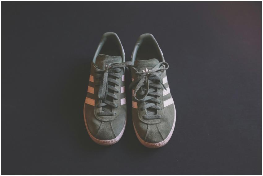 Stylish green sneakers with white stripes on a dar