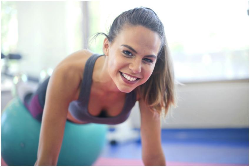 A cheerful woman exercises on a stability ball ind