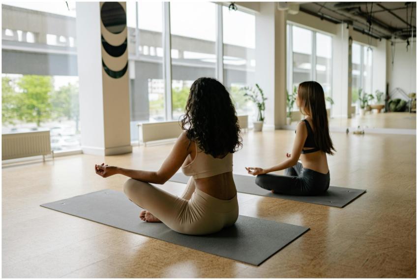 Two women meditating on yoga mats in a modern, pea