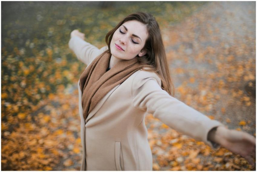 A woman with eyes closed embraces the autumn seaso