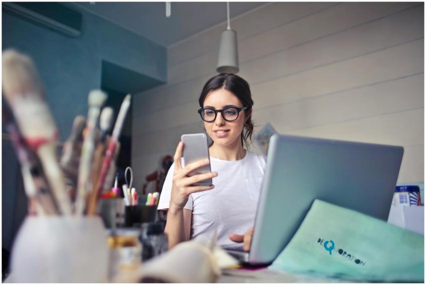 A woman using her phone at a desk, surrounded by a