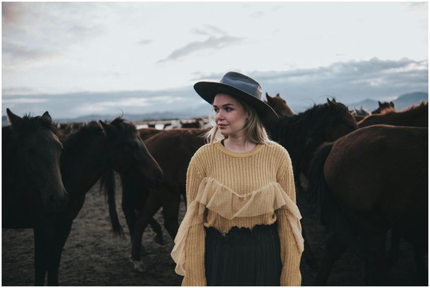 Woman in a stylish outfit and hat standing among a