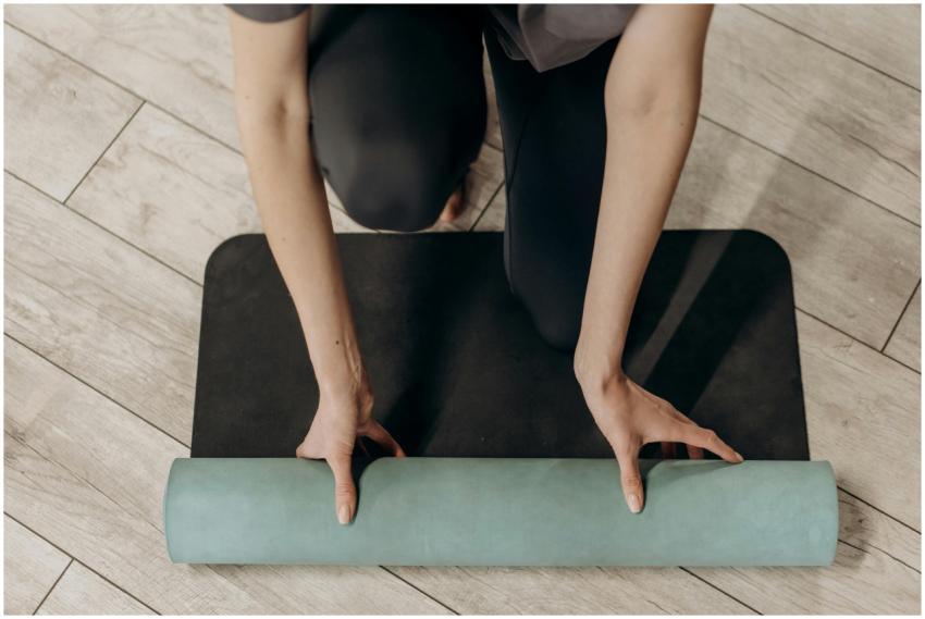 Close-up of individual rolling out a yoga mat on w