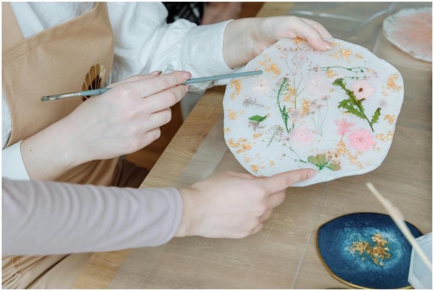 Close-up of hands creating resin artwork with drie