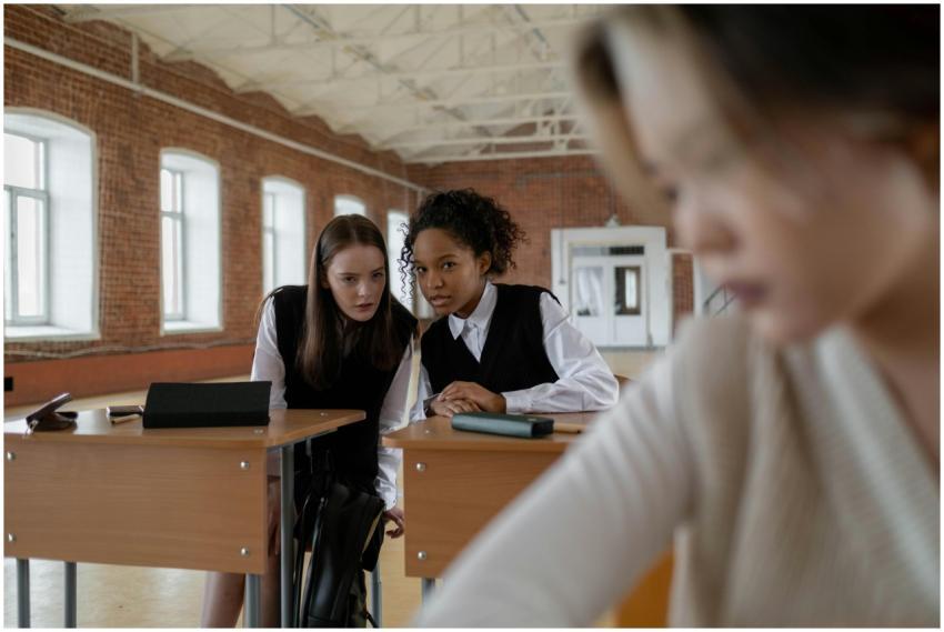 A group of teenagers whispering in a classroom set