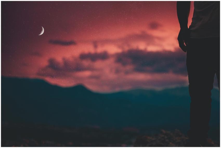 A lone silhouette against a vibrant red twilight s