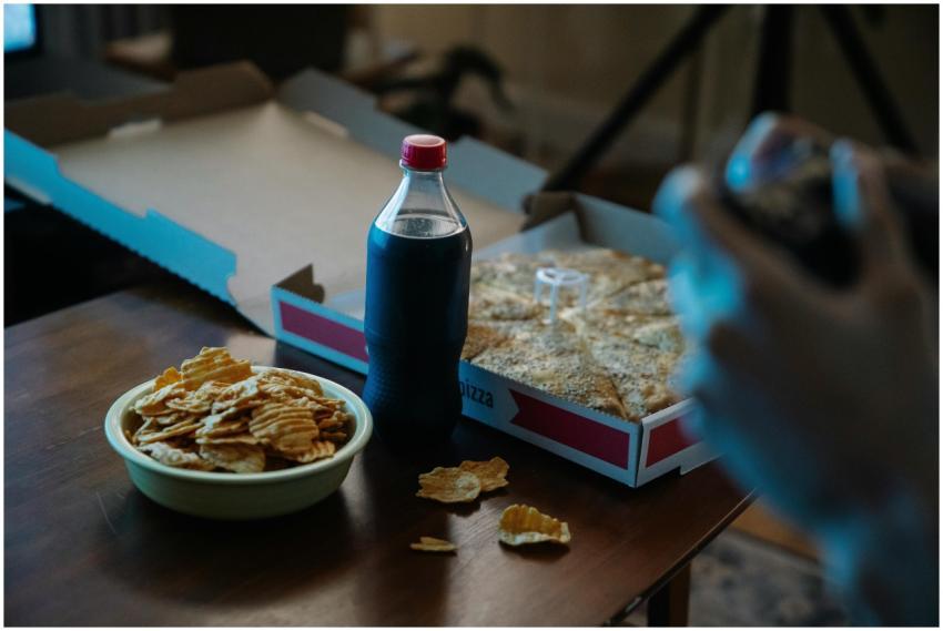 A table set with pizza, chips, and soda, perfect f