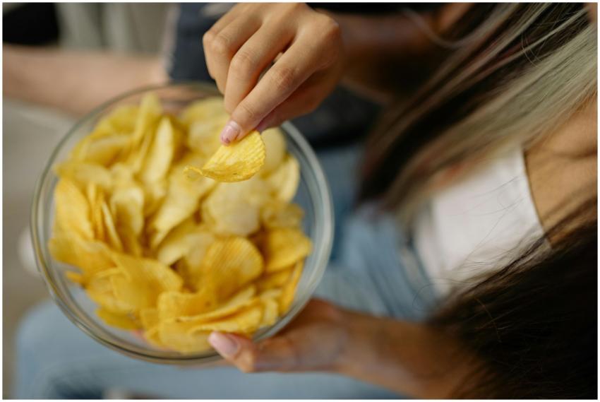 A person reaches for potato chips in a bowl, captu
