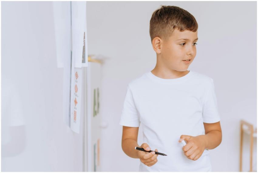A young boy studying with a pen in a classroom, em