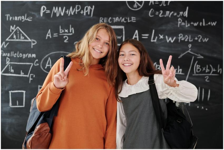 Two smiling students with backpacks in front of a