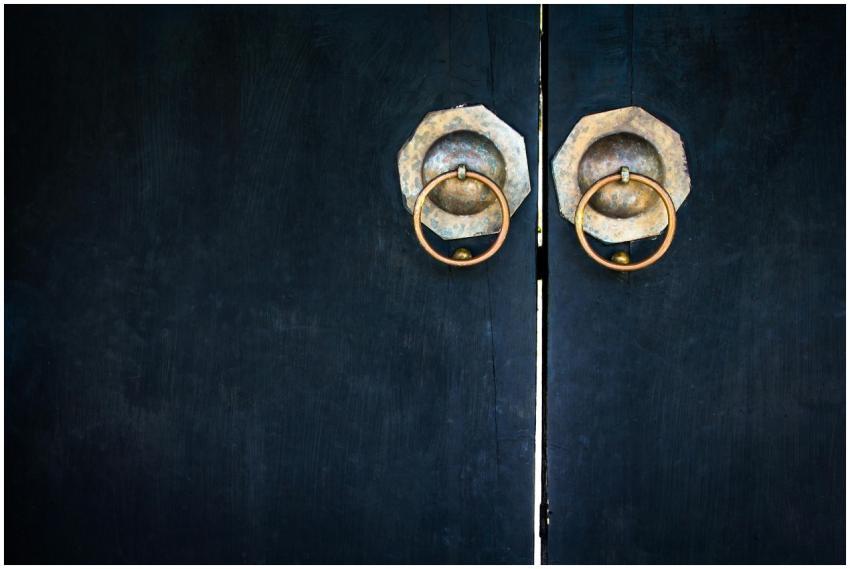 Close-up of vintage wooden doors featuring brass c