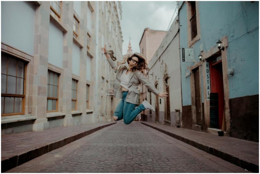 A stylish woman jumps joyfully in a vibrant city s