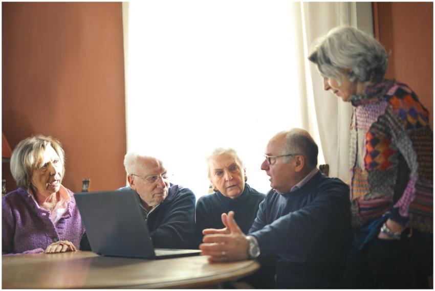Group of senior adults discussing around a laptop