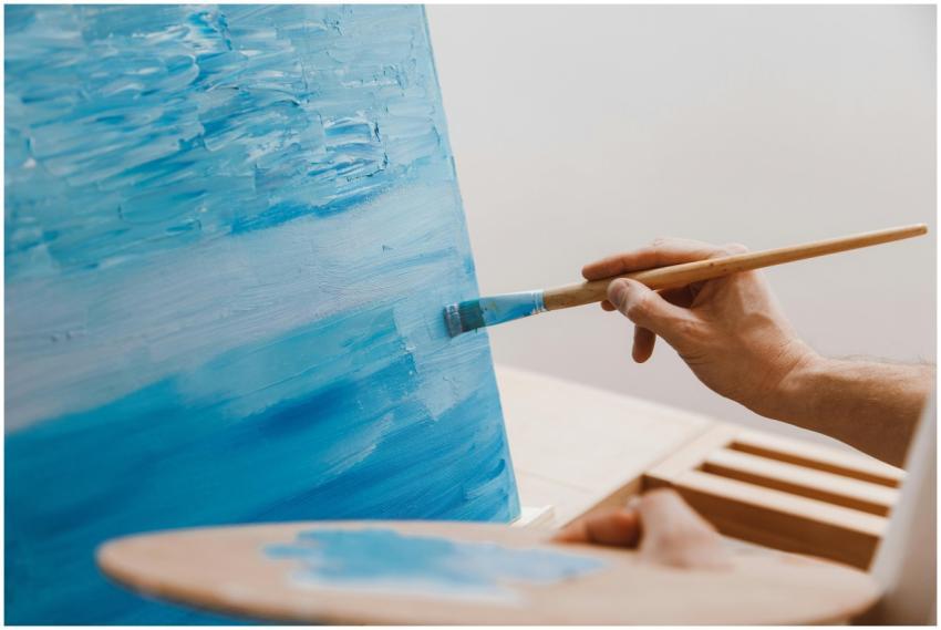 A close-up image of an artist using a brush to pai