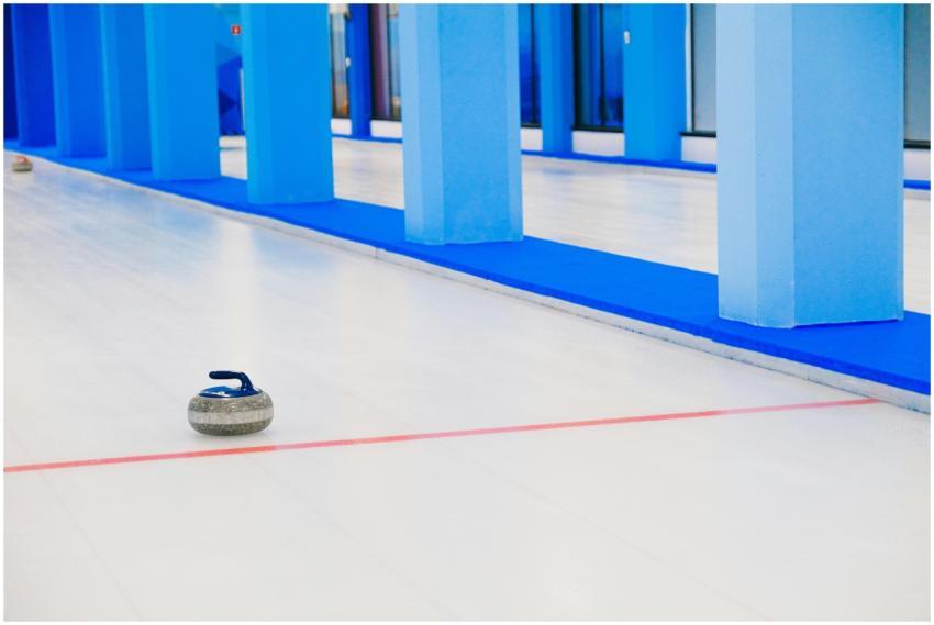 Curling stone on a brightly lit modern ice rink in