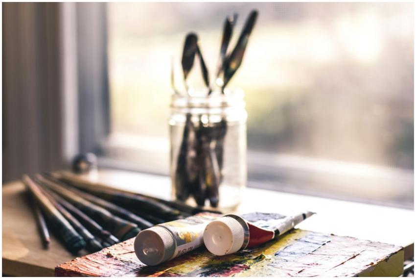 Sunlit table with art supplies, including brushes