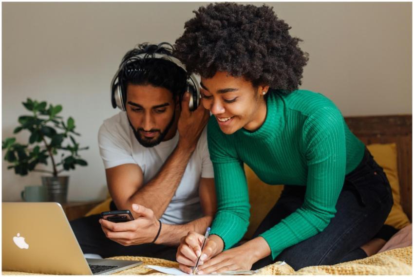 A smiling couple working together at home with lap