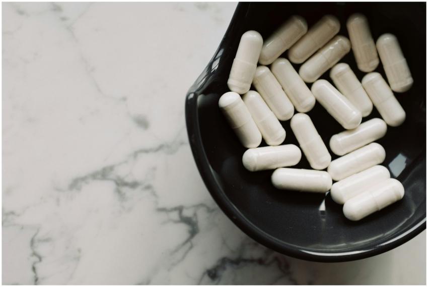 Close-up of white capsules in a black bowl on a ma