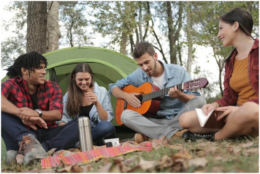 Young friends camping and enjoying music together