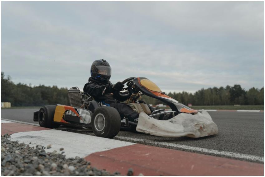 A go-kart driver in full gear navigating a racetra