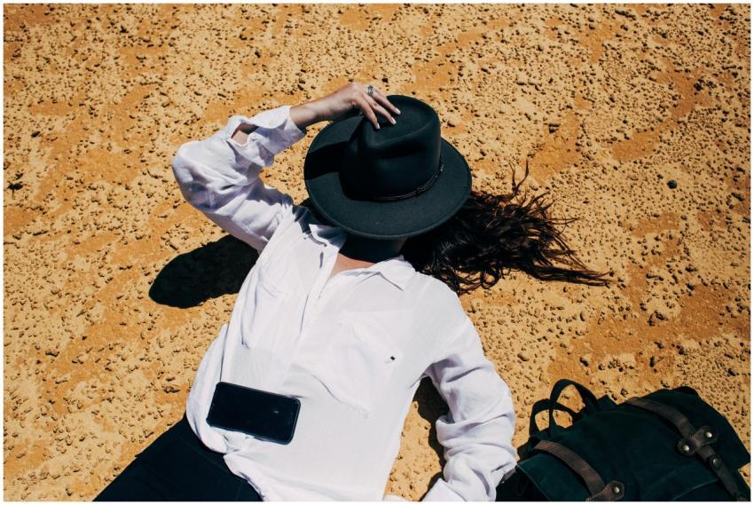 Woman in white blouse and hat relaxing on sandy be