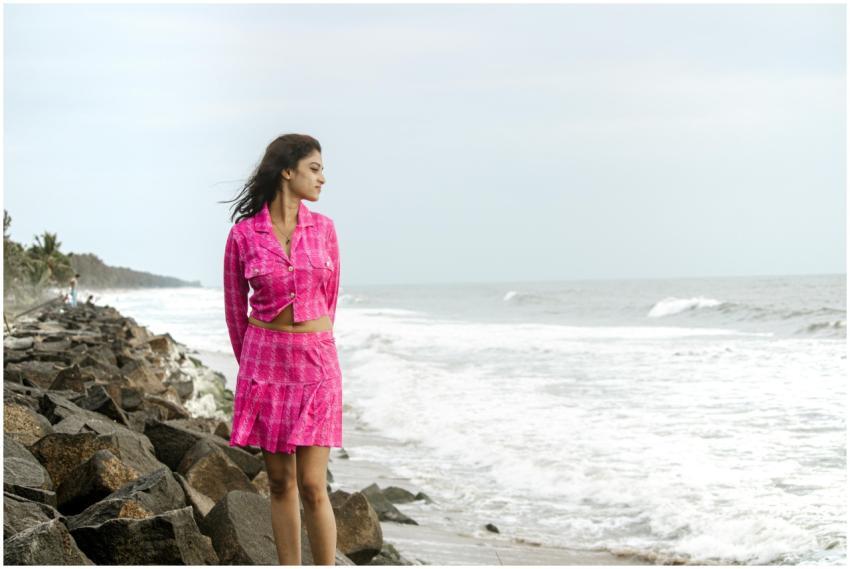 Young woman in vibrant pink dress standing by rock