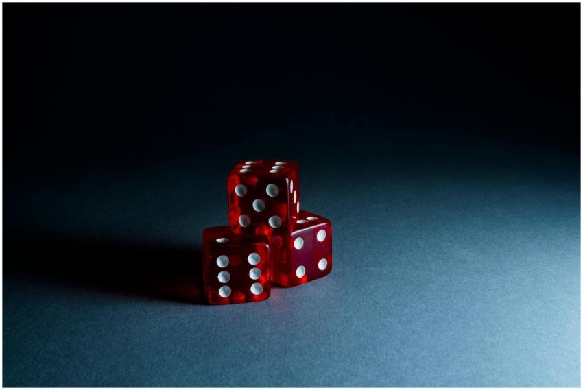 Three red transparent dice stacked on a dark surfa