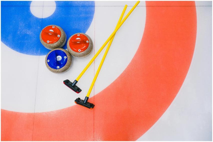 Curling stones and brooms on a colorful ice rink.