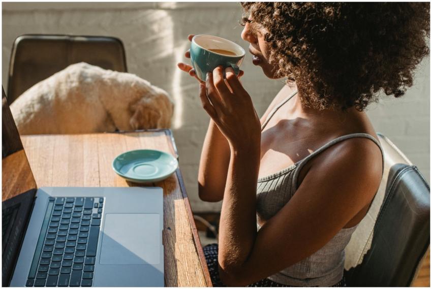 A woman enjoys coffee while working on a laptop at