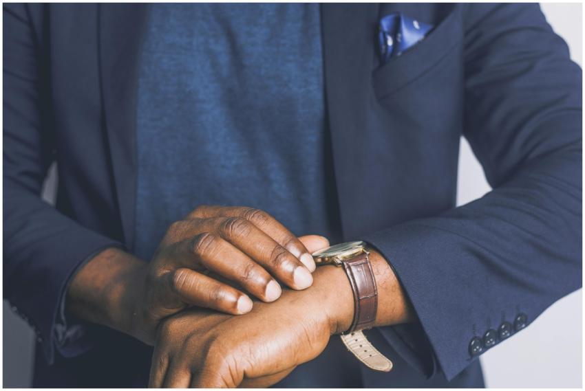 A close-up of a man in a suit checking his wristwa