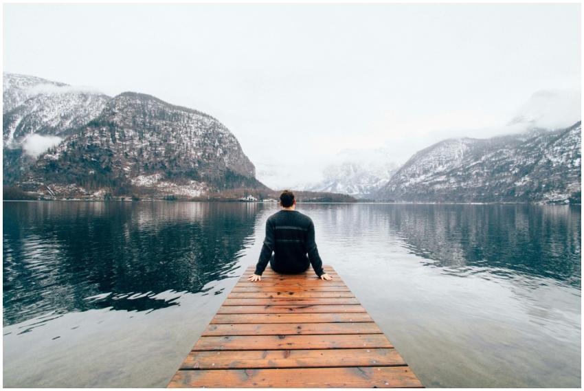A person sitting on a dock, overlooking snowy moun