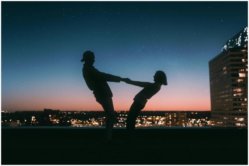 A couple silhouetted against a starry sky on a roo