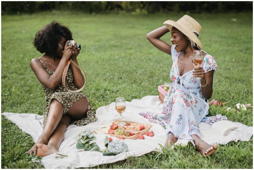 Two women enjoying a vibrant picnic outdoors, capt
