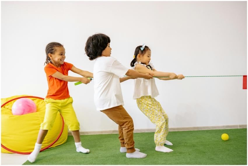 Three children joyfully play tug of war indoors, s