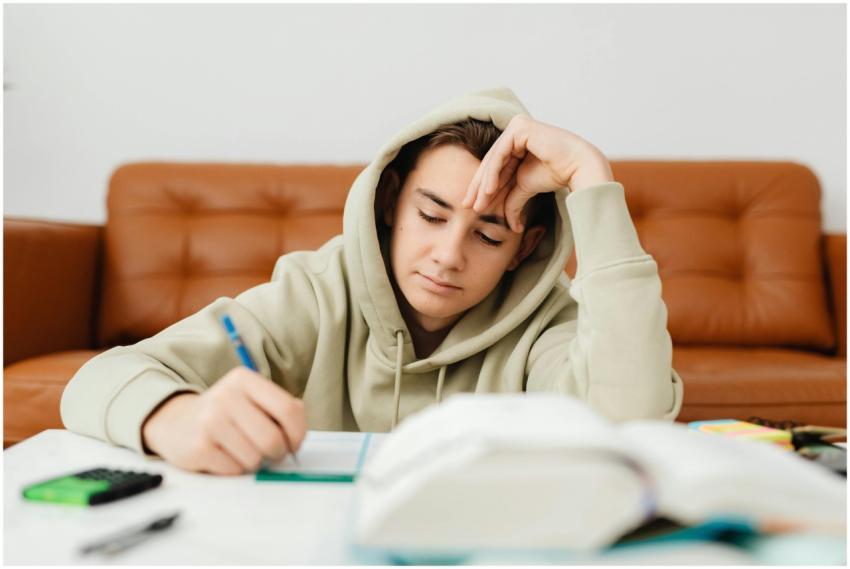 Teenage boy in a hoodie studying at home, focused