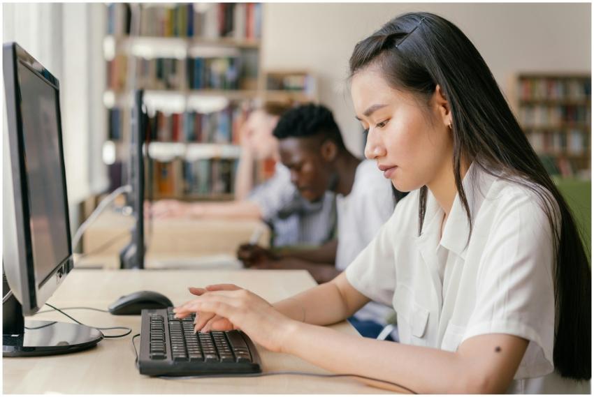 Students using computers in a library, focused on