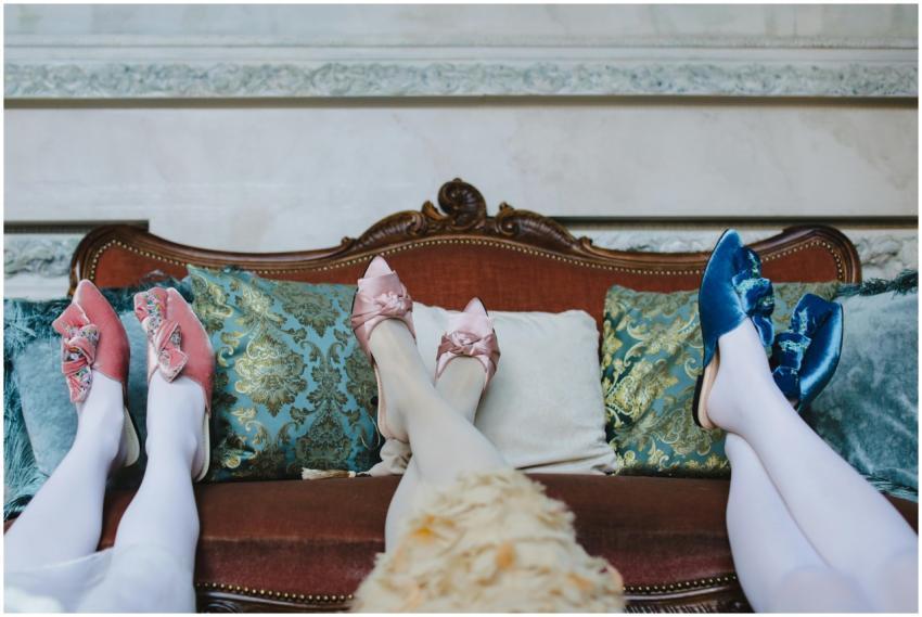 Vibrant loafer sandals on legs with ornate sofa an