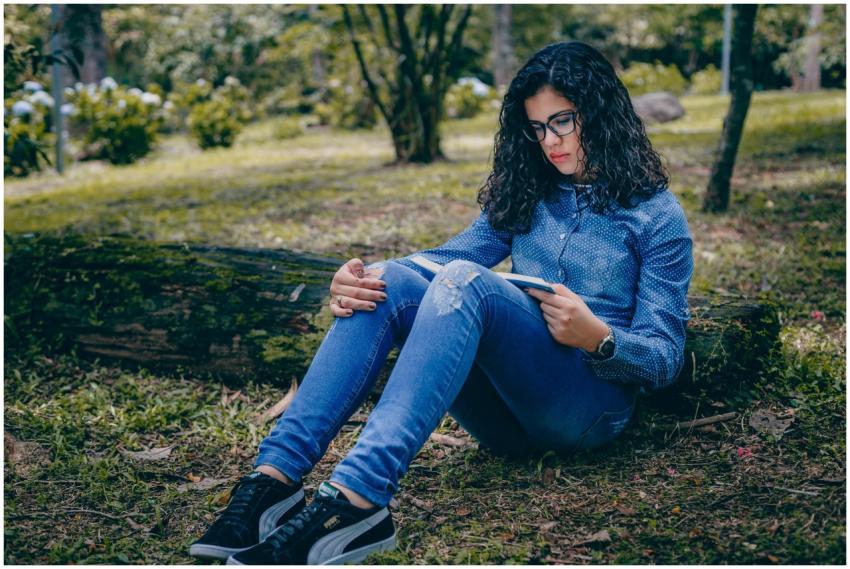 A young woman sitting and reading a book in a peac