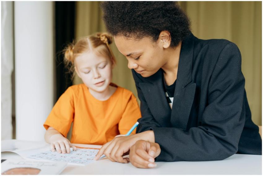 A teacher helps a young student with writing tasks