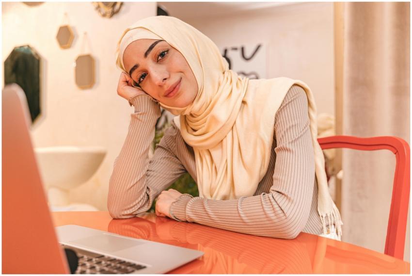 Portrait of a smiling woman in hijab working at ho