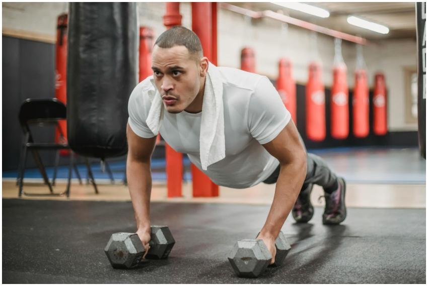 Focused man performing push-ups using dumbbells in