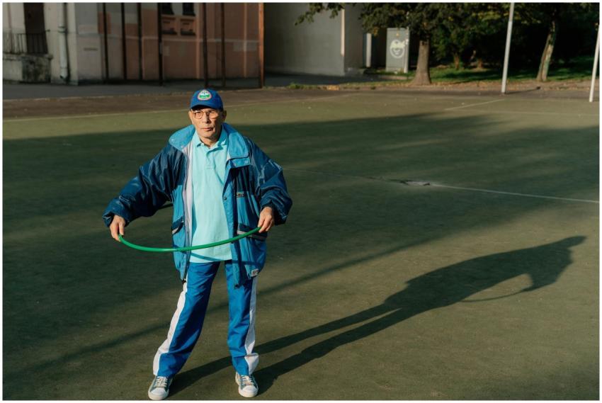 Senior man in athletic gear exercises with a hula