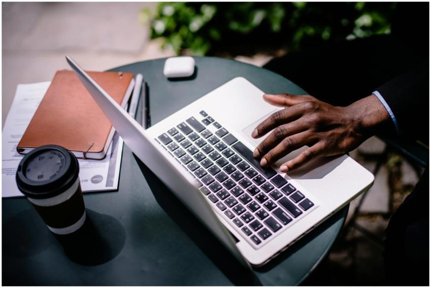 A businessman uses a laptop at an outdoor cafe tab