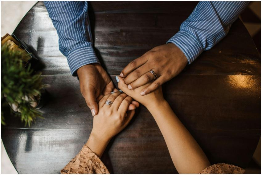 A couple holding hands on a wooden table, expressi